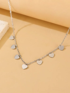 Detailed macro view of silver stainless steel chain with seven heart charms on a stone surface