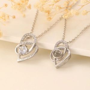 Macro detail of silver heart pendants with 100 languages projection and engraved text