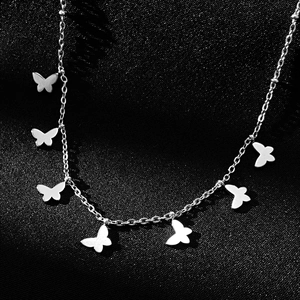 Detailed close-up of a silver titanium steel necklace with seven butterfly pendants on black