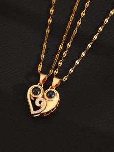 Macro shot of gold heart projection pendant necklaces with zircons on black leather