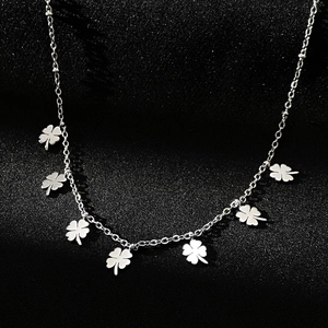 Macro shot of silver stainless steel clover pendant necklace on black textured fabric