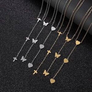 Detail view of steel tassel necklaces with cross and heart pendants on dark glitter background