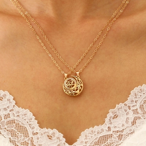 Detail of layered gold sun and moon necklace on model with white lace collar