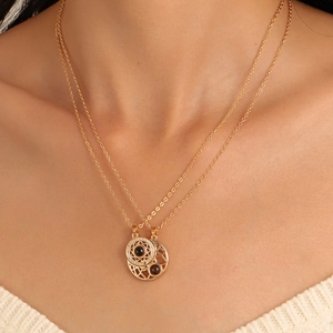Detail of layered gold sun pendant necklace with magnetic clasp on a female neck