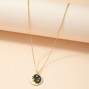 Detailed macro view of a gold celestial necklace with black sun and moon pendant