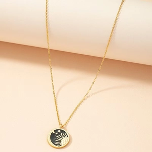 Detail of golden sun and moon pendant with black enamel inlay on a fine chain