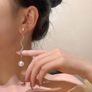 Detailansicht eines eleganten Goldohrrings mit Diamantkette und großer weißer Perle