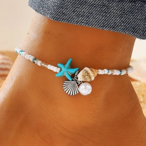 Bohemian seashell and starfish beaded anklet for beach vacation on a sandy background