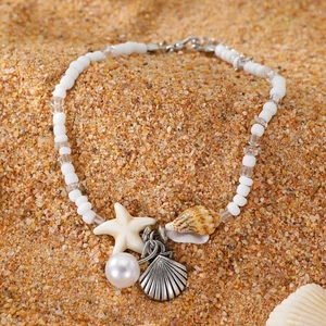 Detailed beach jewelry display with starfish, shell charms, and white beads on sand