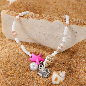 Detail of beach anklet with starfish and shell charms on a sandy background