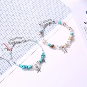 Detailed macro view of starfish charms, natural shells, and blue stone beads on anklets