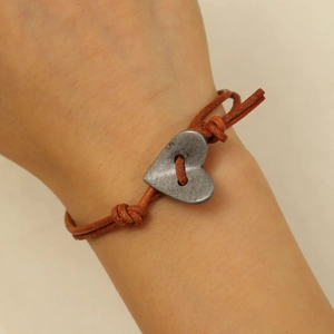 Detailopname van vintage hartvormige hanger op bruin lederen armband voor dames
