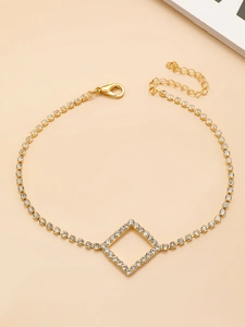Détail d'une chevillère dorée en strass avec pendentif géométrique et fermoir homard