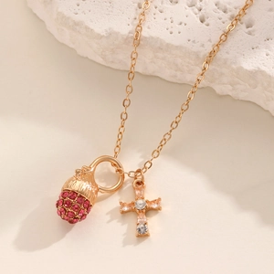 Detailaufnahme einer goldenen Halskette mit rosa Strass-Eichel und Kristall-Kreuz-Anhänger