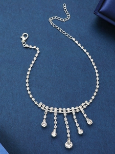 Détail d'une chaîne de cheville argentée avec pompons en strass et fermoir ajustable