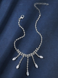 Détail d'une chevillère argentée à pompons en strass avec gemmes marquises sur satin