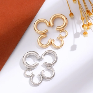 Detail of C-shaped punk ear clips in gold and silver finish with flower-shaped ring design