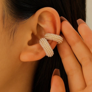 Primo piano di ear cuff dorati con perle bianche fitte per un look sofisticato