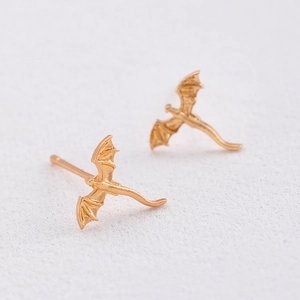 Macro detail of golden dragon stud earrings showing intricate wing scales and textures