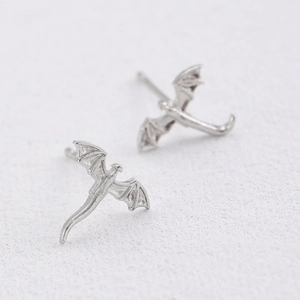 Detailed view of silver flying dragon stud earrings with intricate wing carving and glossy finish