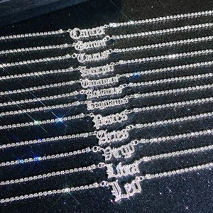 Detail van twaalf dierenriemhangers met kristallen tenniskettingen op zwarte achtergrond