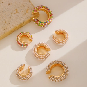 Set di ear cuff vintage in oro con perle e zirconi su sfondo di pietra calda