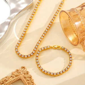 Detailopname van gouden tennis ketting en armband set met sprankelende zirkonia steen