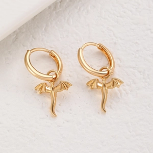 Macro shot of gold dragon pendant earrings with detailed wing texture and polished finish