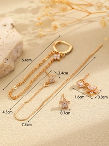 Macro detail of 14K gold hoop earrings set with micro-pave zircons and floral charms