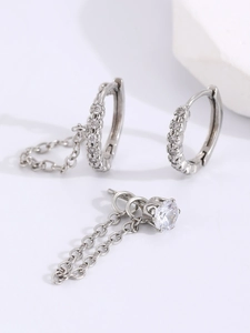 Detailed macro view of silver hoop earrings with micro-set zircons and elegant chain charms