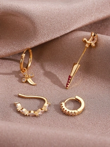 Detailed macro view of 14K gold-plated earring set with red zircon and dagger charm