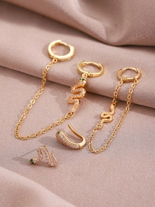 Detailed set of 14K gold snake earrings with white zircons and green stone eyes on silk