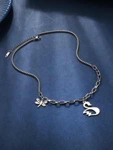 Detail of silver splice chain necklace with dragonfly and swan charms on blue surface