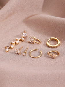 Detail of 7-piece set 14K gold-plated earrings with cubic zirconia on beige silk fabric