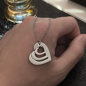 Detail showing the layered triple heart pendant on a silver-toned stainless steel chain