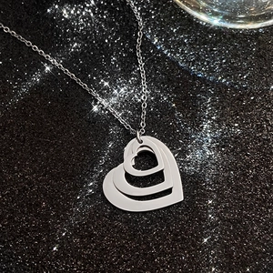 Close-up of three-layered silver heart pendant necklace on a premium black background