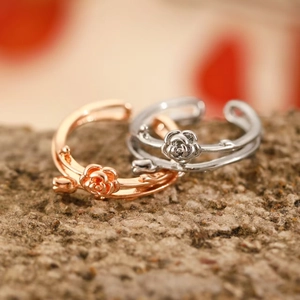 Close-up of rose flower rings in rose gold and silver on natural stone background