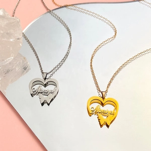 Macro shot of custom heart name necklace with butterfly detail in gold and silver