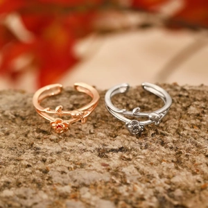Detailed macro view of rose gold and silver floral rings on a textured stone surface