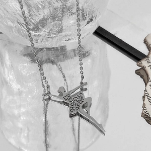 Artistic macro shot of a silver ballet dancer pendant with intricate镂空patterns on a chain