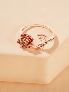 Detailed view of rose gold floral ring with rose flower and leaf on warm background