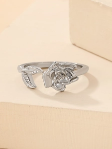 Macro detail of silver rose and leaf open ring on a minimalist pedestal base