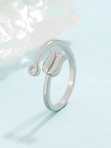 Macro shot of silver tulip ring with sparkling zircon stone on a cool ice-blue background