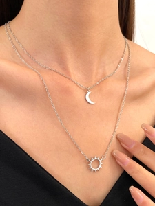 Close-up of double-layer silver necklace with sun and crescent moon pendants on a model