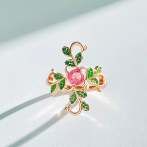 Macro shot of rose gold ring with a pink gemstone and green enamel vine details