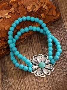 Detail of bohemian turquoise wood bead bracelet with large silver hollow flower charm