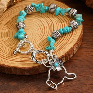 Detail of bohemian turquoise beaded bracelet with vintage flower pendant on wooden tray