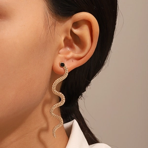 Macro detail of golden snake earring featuring scale texture and black stone eye detail