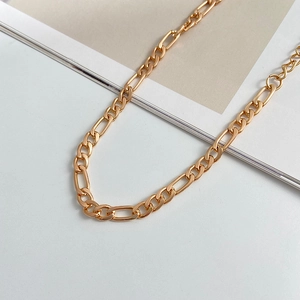 Detail of golden Figaro chain bracelet featuring alternating short and long metal links
