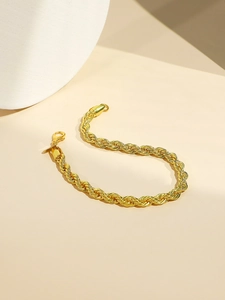 Close-up of golden rope chain bracelet with lobster clasp on a beige surface